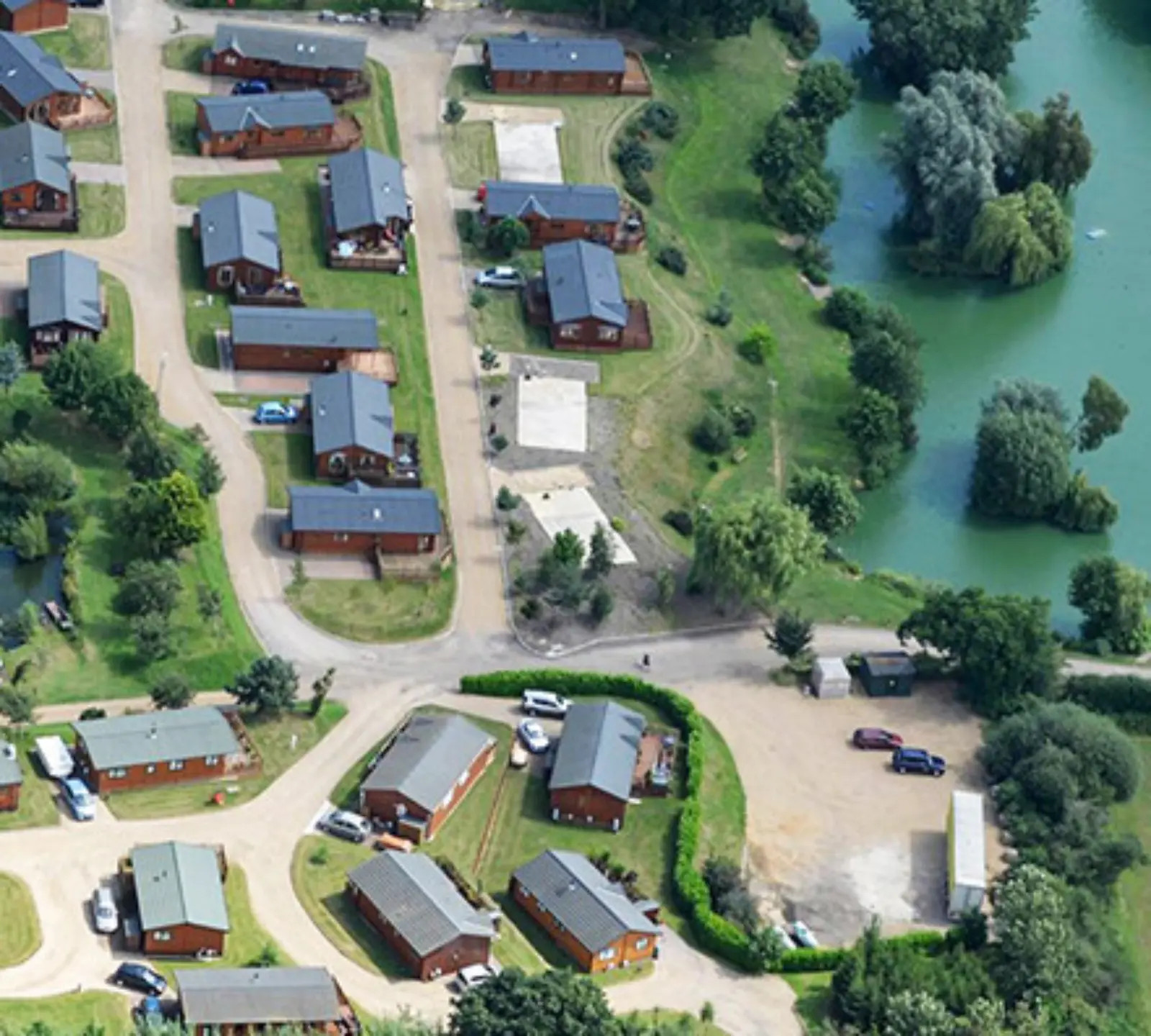 Aerial view of a residential neighborhood with individual houses, roads, and surrounding greenery near a body of water on the right side.