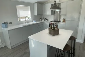 Modern kitchen with white cabinetry, a central island with stools, a window above the sink, and stainless steel appliances.