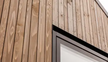 Close-up of a wooden exterior wall with vertical timber cladding and minimalist window, showcasing modern architectural design and sustainable material texture