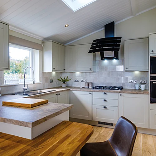 Bright kitchen with beige cabinets, a window above the sink, a wooden table, and modern appliances including a microwave and oven.