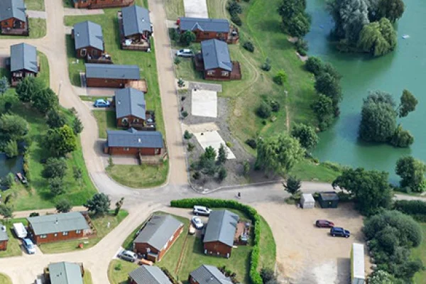 Aerial view of a residential neighborhood with individual houses, roads, and surrounding greenery near a body of water on the right side.
